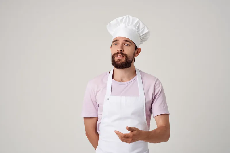 Шеф-повар в белом фартуке на профессиональной кухне ресторана