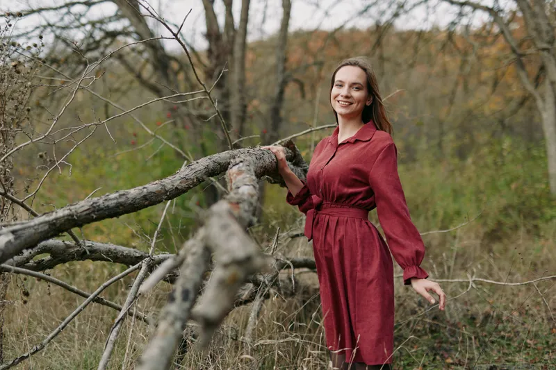 An authentic portrait of a woman in a red dress outdoors, featuring natural light, candid pose, and a calm, real atmosphere that emphasizes authenticity and charm.