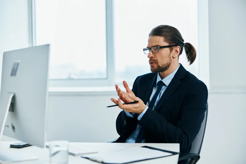 Мужчина в костюме работает за компьютером с документами, руководитель