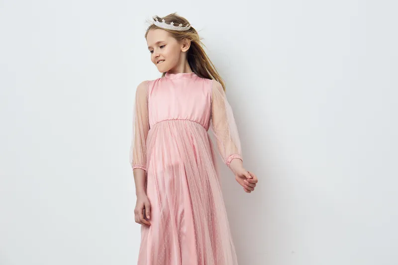 Lovely young girl in a pink dress, exuding joy and confidence, with soft blonde hair and a dreamy atmosphere, perfect for children s fashion concepts