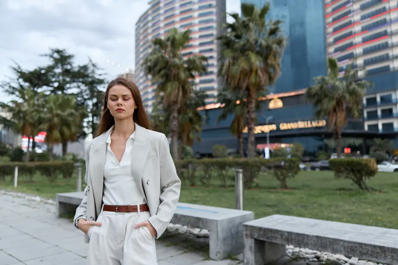 Confident businesswoman in a stylish gray suit standing outdoors, exuding professionalism against a modern cityscape.