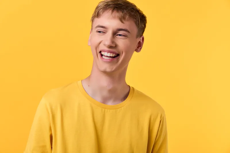 Smiling young man in a bright yellow shirt against a vivid yellow backdrop, conveying cheerful mood, casual fashion and positive energy for lifestyle, happiness, and modern branding in marketing and