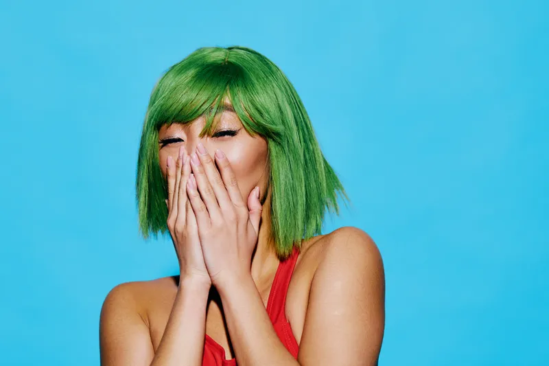 Эмоциональная женщина азиатской внешности в шляпе, красном и ретро-стиле, с улыбкой и удивлённым выражением лица
