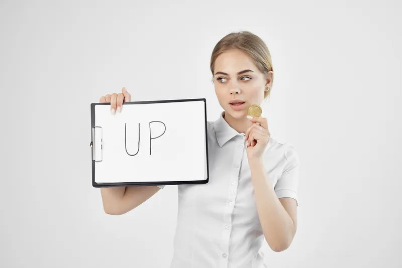 Деловая женщина держит в руках бумагу с надписью «Bitcoin» и символом криптовалюты