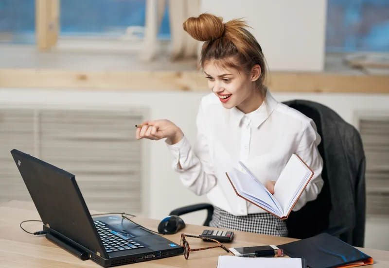 Уставшая деловая женщина работает в офисе, используя технологии