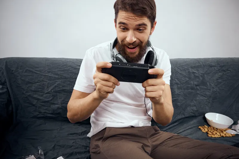 Мужчина сидит на диване с геймпадом в руке