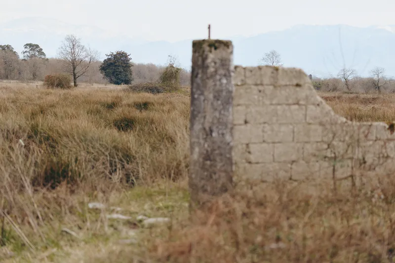Outdoor rural landscape, dry grass, stone wall, weathered post, field view, calm rural atmosphere, soft daylight, minimalist nature lifestyle, quiet background