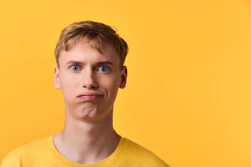 Puzzled expression, young man in casual yellow tee against a bright backdrop, conveying confusion, curiosity, and uncertainty in everyday moments.