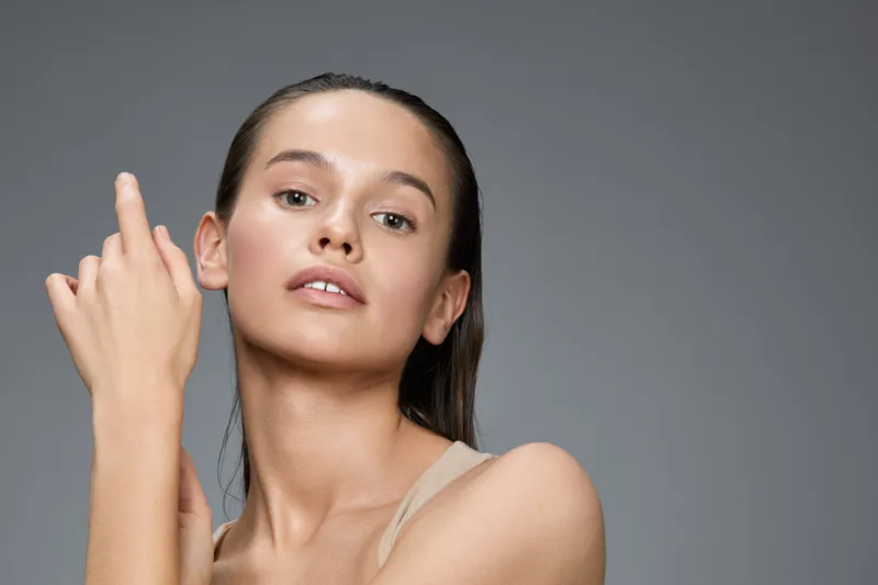 Young woman with natural beauty showcasing soft skincare routine in minimalist style, emphasizing glowing skin and healthy self care