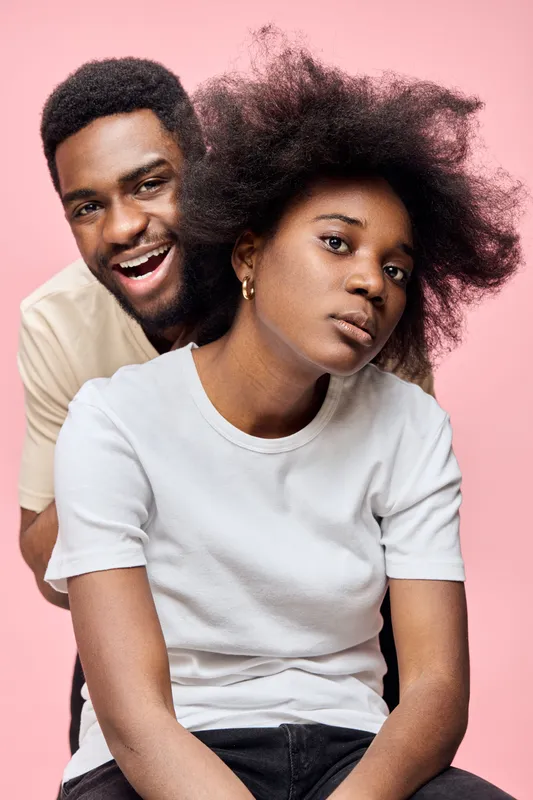 Young African couple with natural hairstyles, exuding confidence against a pink background, ideal for lifestyle and beauty concepts