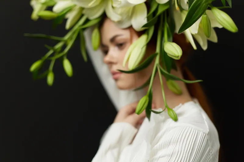 Beautiful young woman with floral headpiece, showcasing elegance and tranquility in a serene atmosphere with a dark background and soft lighting