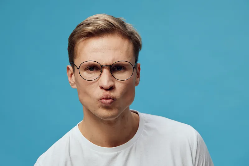 puzzled man wearing glasses white tshirt blue background closeup studio portrait face expression digital detox concept