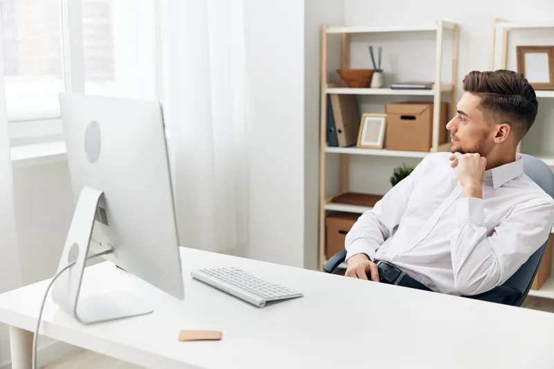 Менеджер сидит за столом перед компьютером с клавиатурой