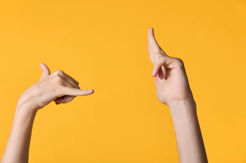 Framing by two hands against a bright orange background, showcasing a creative photography gesture and composition for visual storytelling, minimal setup, dynamic negative space, and playful