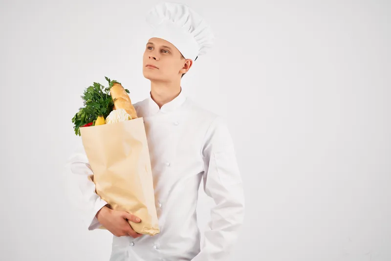 Мужчина-шеф-повар с пакетом продуктов в ресторане