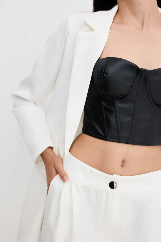 woman fashion dressed in white suit with black corset top, stylish outfit, modern clothing, minimalistic studio background, cropped frame