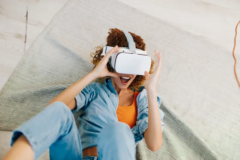 Радость виртуальной реальности: женщина наслаждается футуристической VR-игрой дома, в помещении