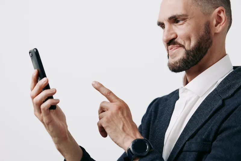 Professional man in business attire uses a smartphone, showing confident and thoughtful emotion, on an isolated colored background suitable for corporate or tech themes.