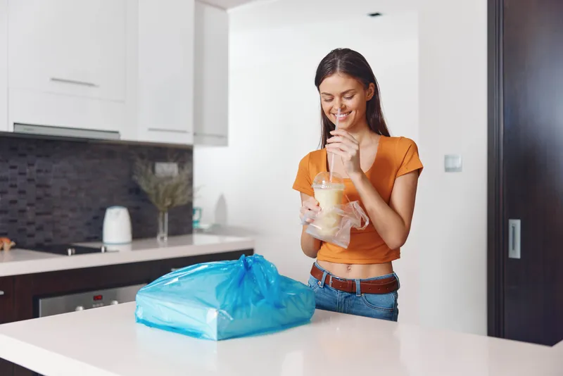 Женщина стоит на кухне с пакетом продуктов перед собой, готовясь приготовить ужин