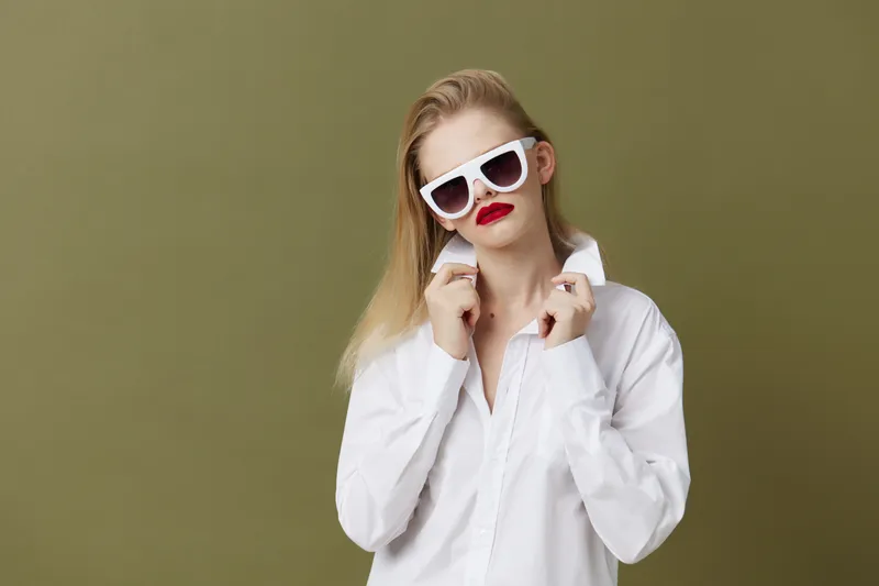 Портрет женщины в модной белой рубашке и солнцезащитных очках на изолированном фоне