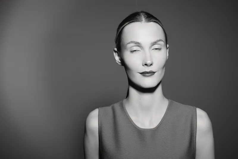 Portrait of a fair skinned white woman with closed eyes in black and white photo wearing sleeveless top. Concept of calmness, serenity, and minimalism.