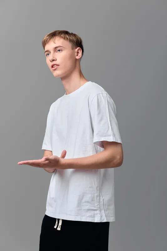 Hands, man, gesture in a studio environment, white t shirt, open palms and focused expression, gray background, minimal composition suitable for lifestyle, education or product advertising contexts