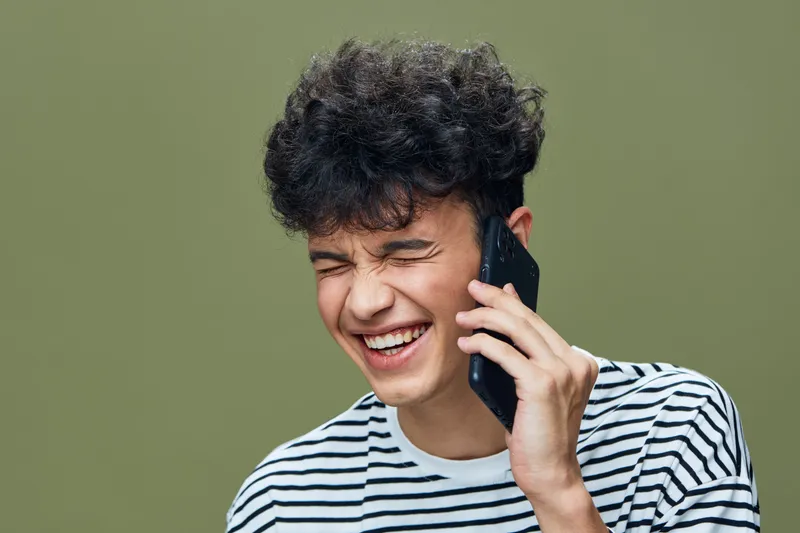 smiling man talking phone joyful expression striped shirt casual outfit green background communication concept