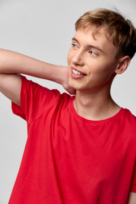 Smiling boy wearing a red shirt poses casually with a relaxed posture and friendly expression, suitable for youth lifestyle, education, and product showcasing contexts.