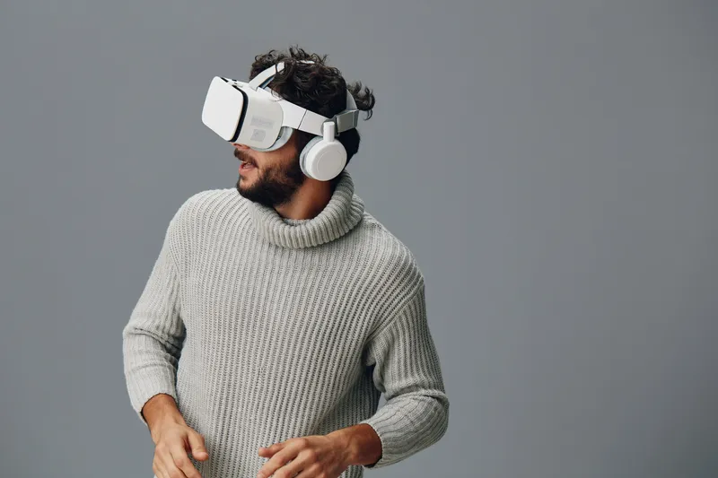 Мужчина в виртуальной реальности: он в наушниках и VR-очках, выражение лица заинтересованное, портрет, современные технологии, развлечения