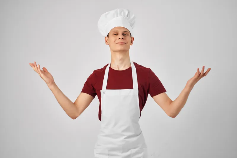 Мужчина-повар в колпаке на голове работает на кухне