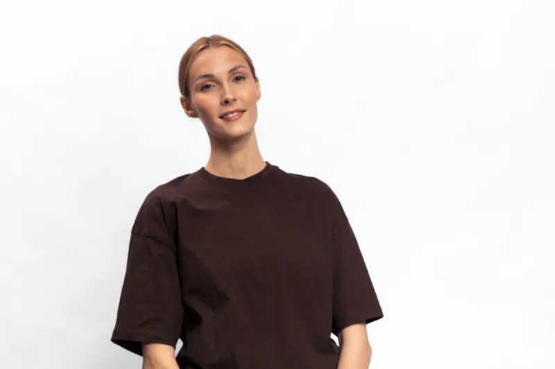 Young woman with light hair wearing a dark t shirt stands smiling on white background. Studio portrait of casual female model with natural makeup and relaxed confident pose.
