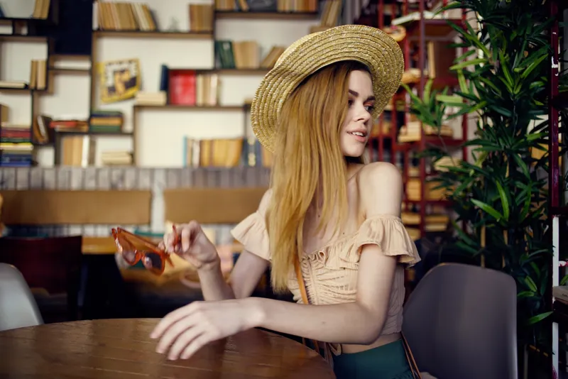 Симпатичная женщина в шляпе с книгой читает во время отдыха в помещении