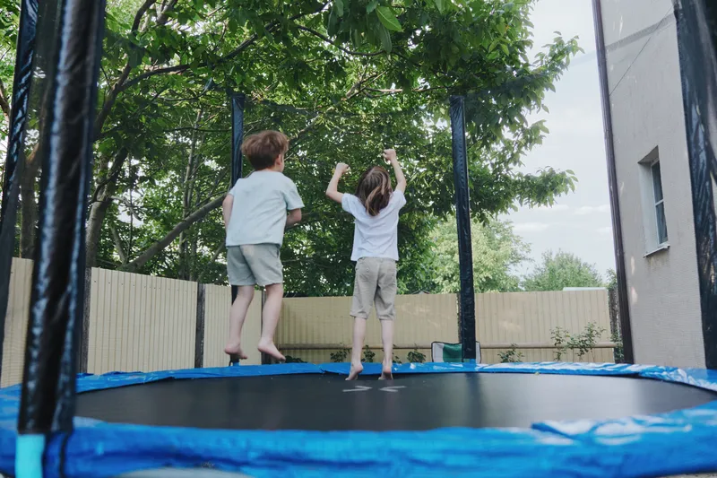 Kids jumping on a trampoline, experiencing pure joy and excitement. Bright and cheerful outdoor setting, capturing playful moments in a fun atmosphere.