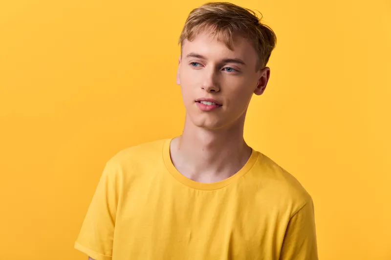 Young man in a yellow shirt against a vibrant yellow studio backdrop, casual fashion mood, clean lighting and minimal composition with warm color harmony