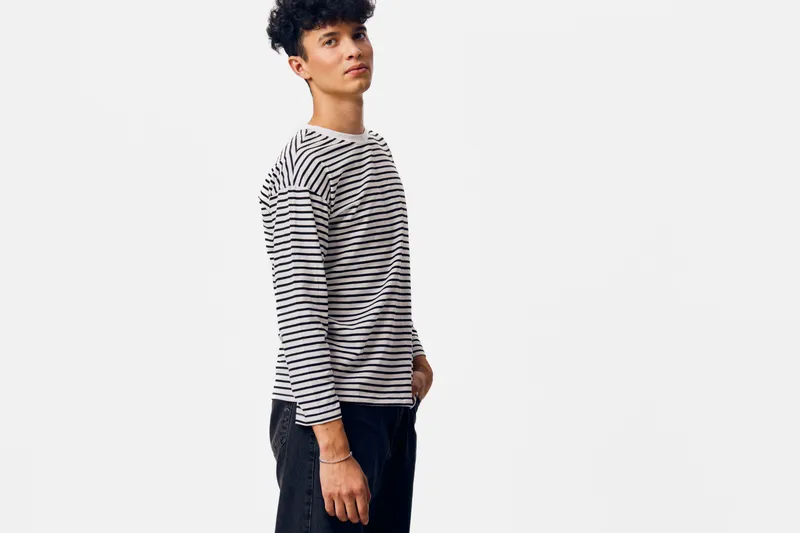 young man wearing striped shirt standing relaxed against white background with casual style and confident expression in studio lighting composition