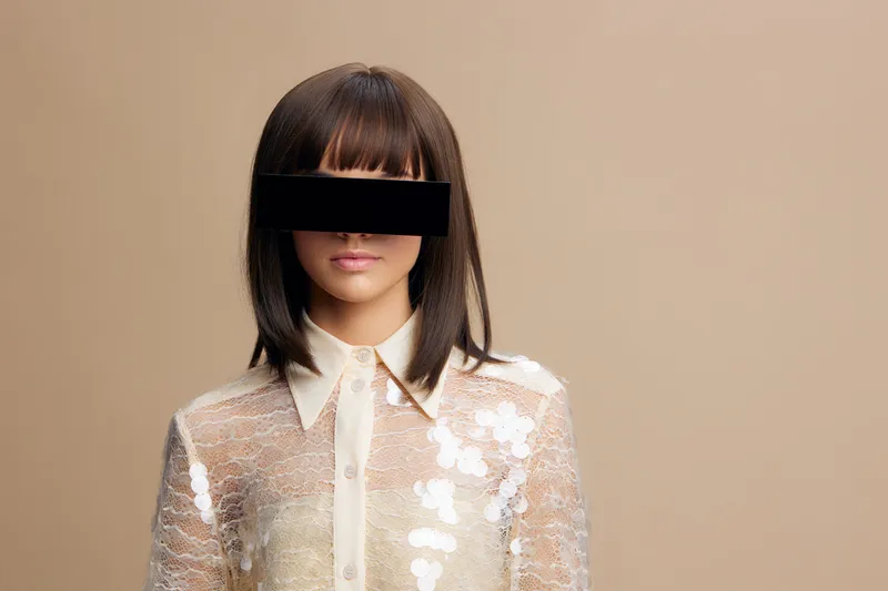 Женщина с завязанными глазами, на ткани повязки написаны слова «blind» (слепой)