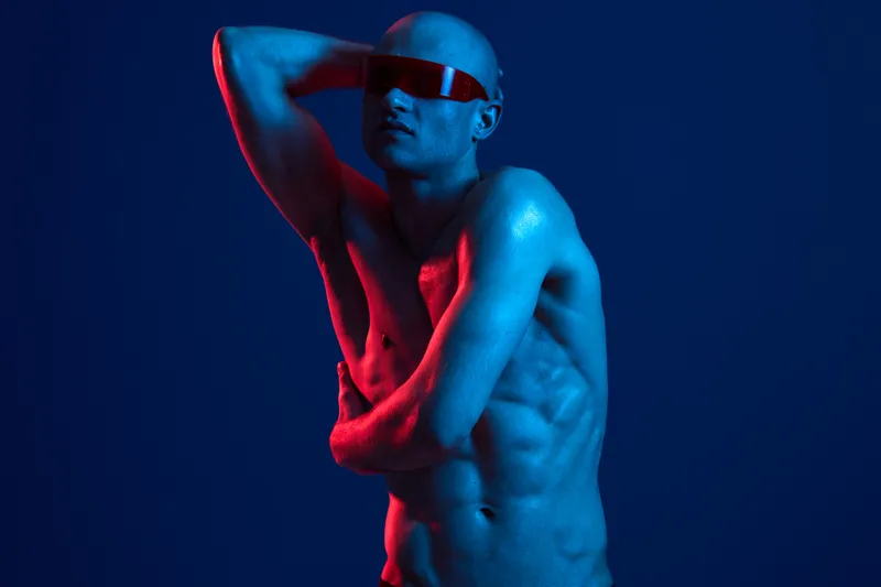 Dynamic man striking a pose under vibrant blue and red lights, exuding confidence and sophistication in this captivating image. Perfect for modern concepts.