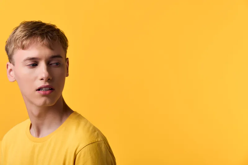 Yellow themed image of a young man in a matching yellow shirt against a vivid yellow backdrop, conveying mood, style and simple fashion appeal for editorial, lifestyle or advertising projects
