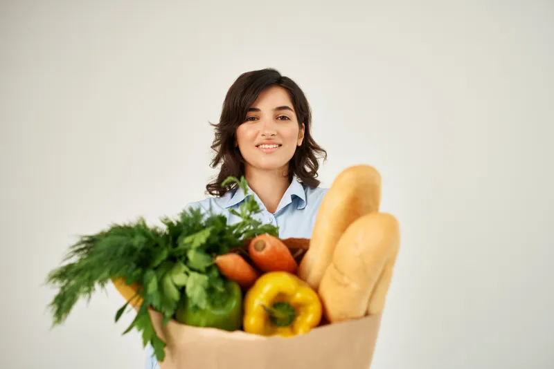 Улыбающаяся женщина в голубой рубашке с пакетом продуктов, овощи, здоровая пища, органические продукты