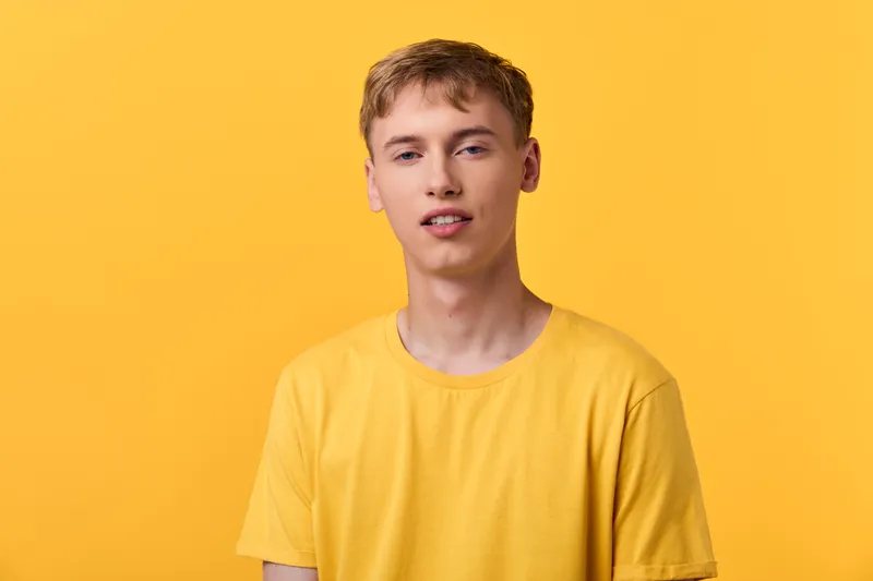 Yellow shirt worn by a young man against a bright background in a minimal studio setting, showcasing casual style and cheerful mood for lifestyle, fashion or advertising stock imagery