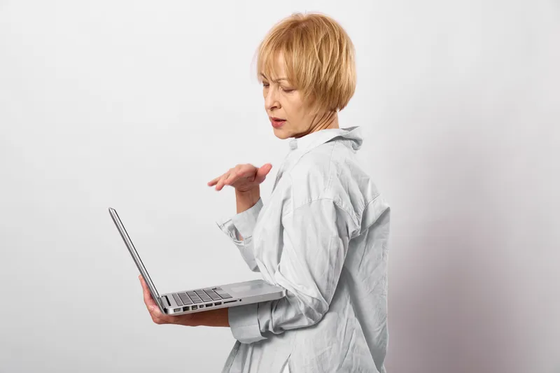 Woman in a white coat holds a laptop, coughing and touching her chest, showing respiratory illness, healthcare stress and anxiety in telemedicine