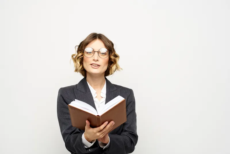 Женщина за работой с книгой в руке на светлом фоне