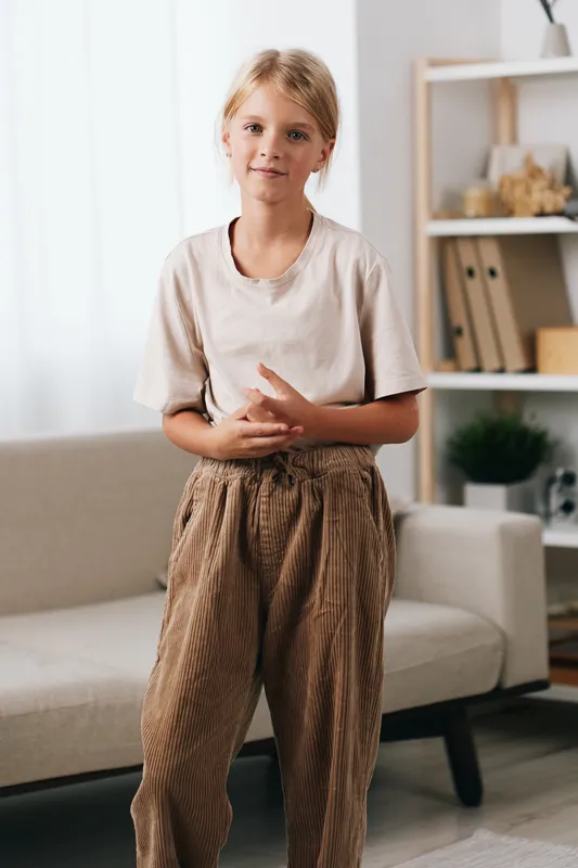 Authenticity shines in this candid lifestyle shot, capturing a young girl in simple attire. The scene hints at school routines, quiet play, and daily light at home.