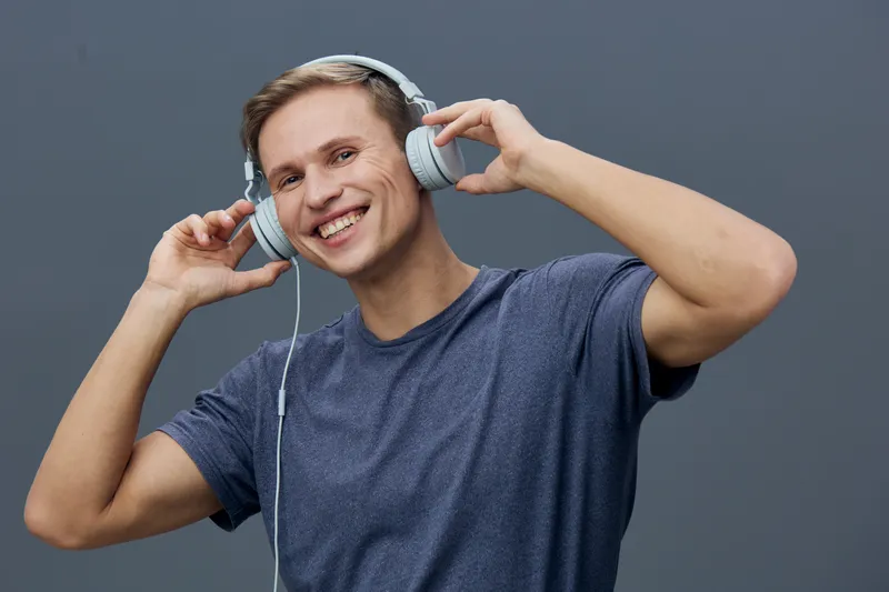 Smiling man wearing headphones listen music hold wired headphones blue t-shirt casual style isolated on grey background digital detox concept