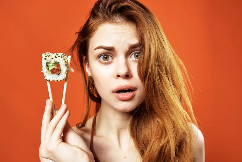 Женщина с палочками для еды и роллами суши, японская кухня, закуска
