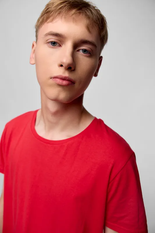Boy, teenager, red shirt, studio shot, closeup, neutral expression, youth, casual clothing, simple background, soft lighting, style, everyday fashion, facial features, candid moment, calm mood,