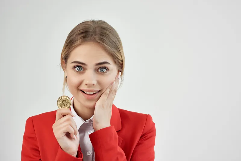 Финансист в красной куртке с золотой монетой Bitcoin на изолированном фоне