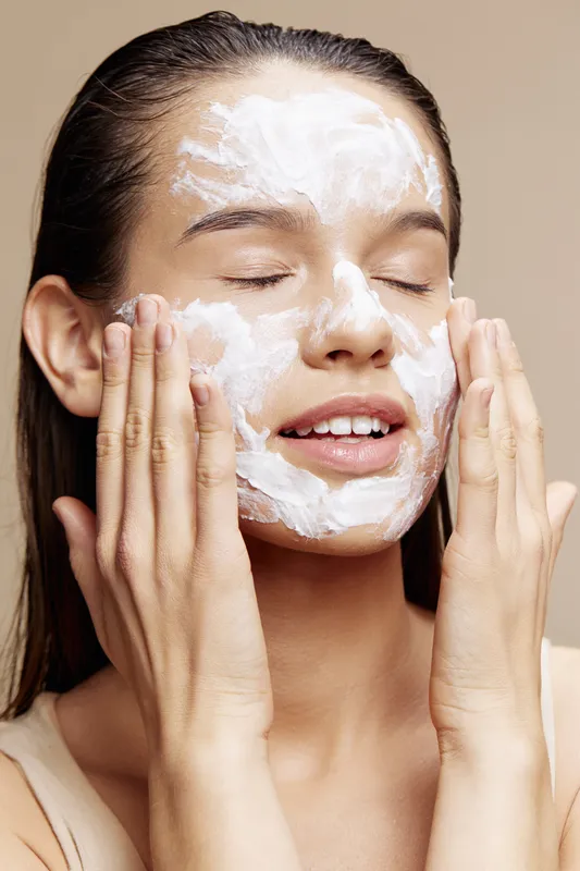 Женщина наносит маску для лица с закрытыми глазами, крупный план, уход за кожей