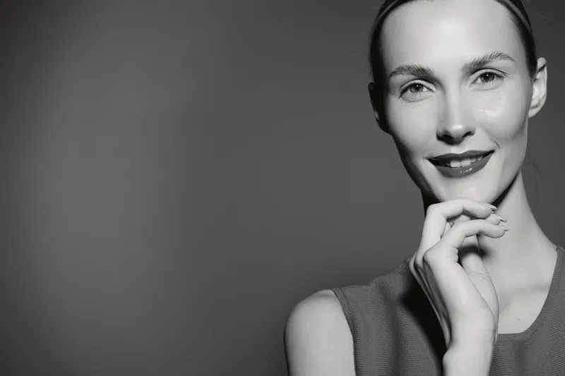 Portrait of a smiling Caucasian woman with fair skin and dark hair in black and white. Concept of beauty, happiness, and confidence.