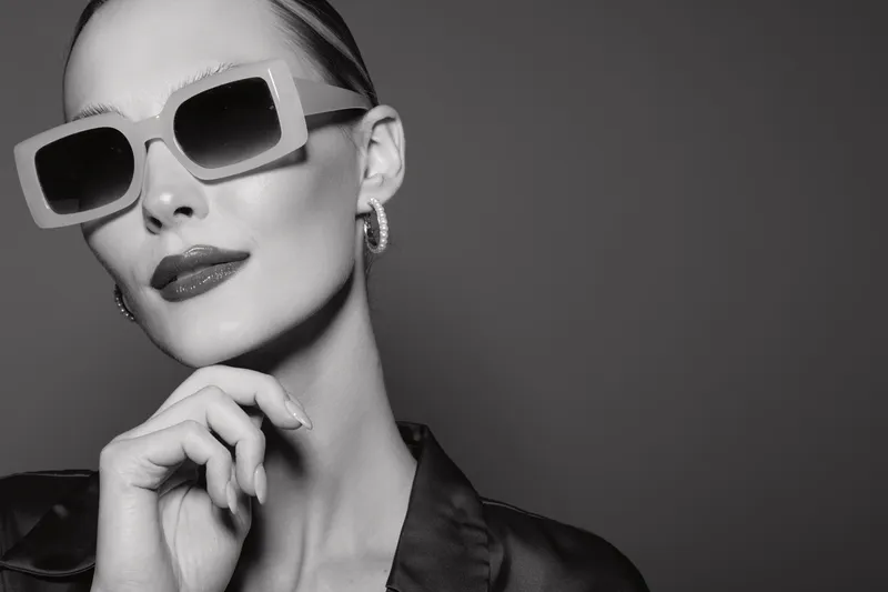 Portrait of a stylish Caucasian woman with pale skin wearing large sunglasses and elegant makeup in monochrome.